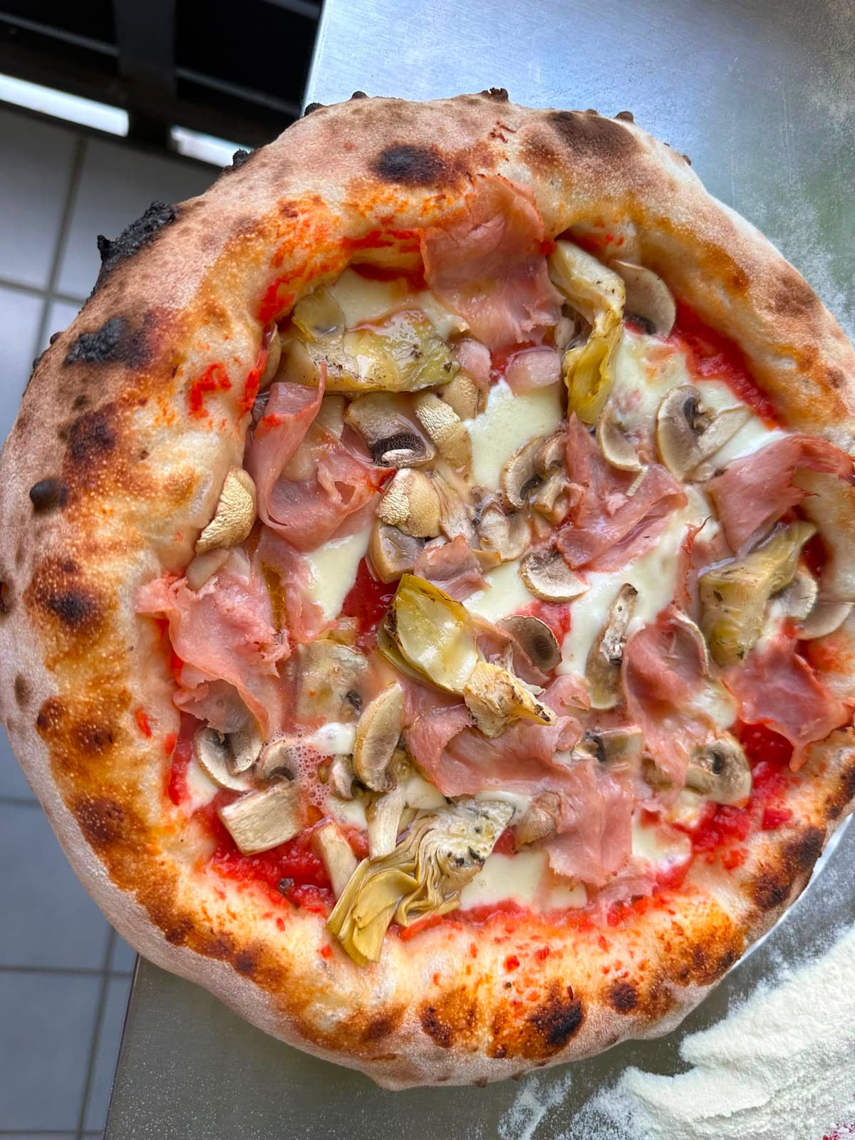 Pizza mit Schinken, Champignons und Artischocken