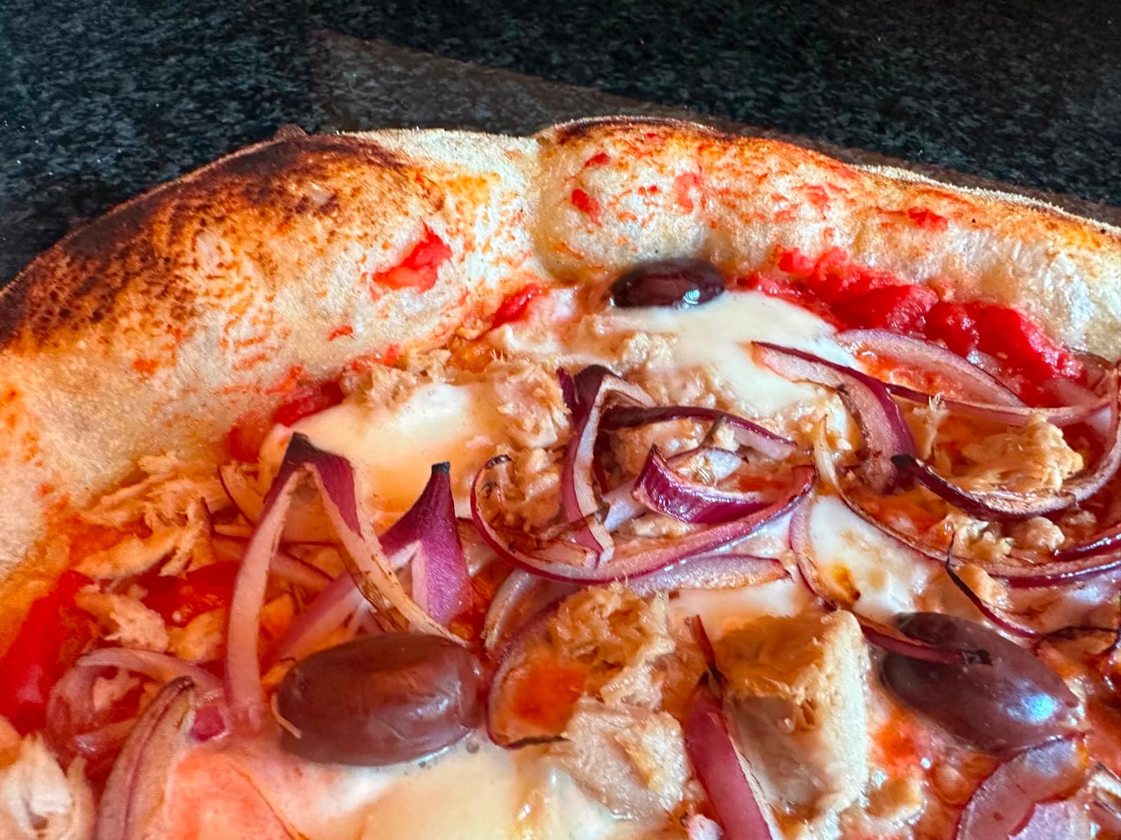 Nahaufnahme einer Pizza mit Thunfisch, Zwiebeln und Oliven