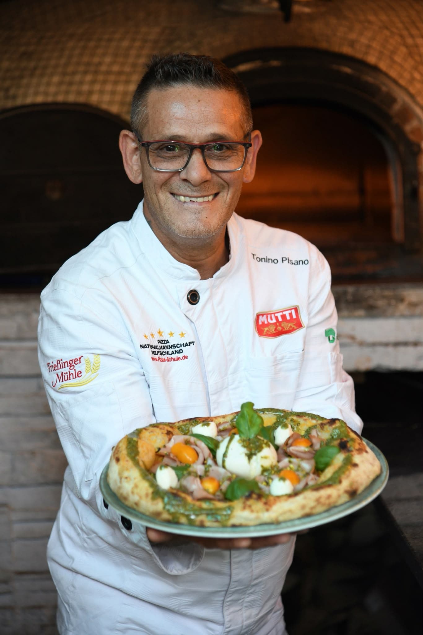Tonino Pisano mit einer Pizza vor dem Steinofen
